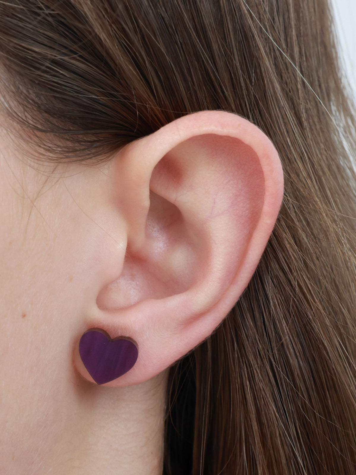 So Loved purple swirl resin acrylic heart stud earrings worn on an ear to show size and fit