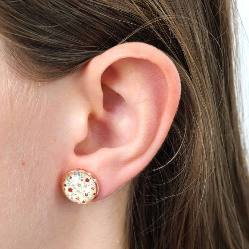 Close-up of an ear wearing a round earring with floral design.