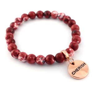 Red beaded bracelet with a 'CHERISH' charm on a white background