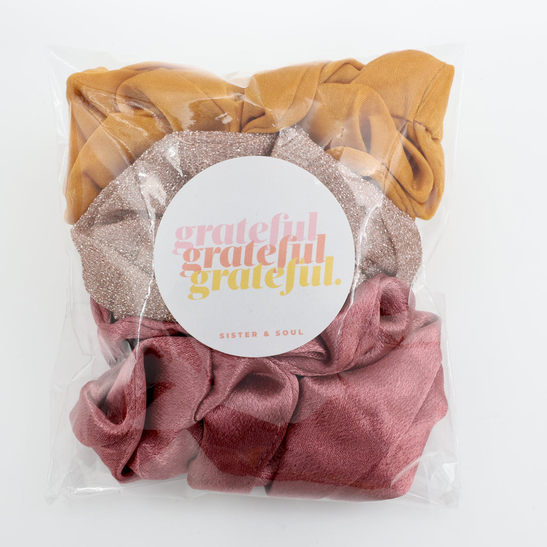 Packaged scrunchies with 'grateful' label on a white background