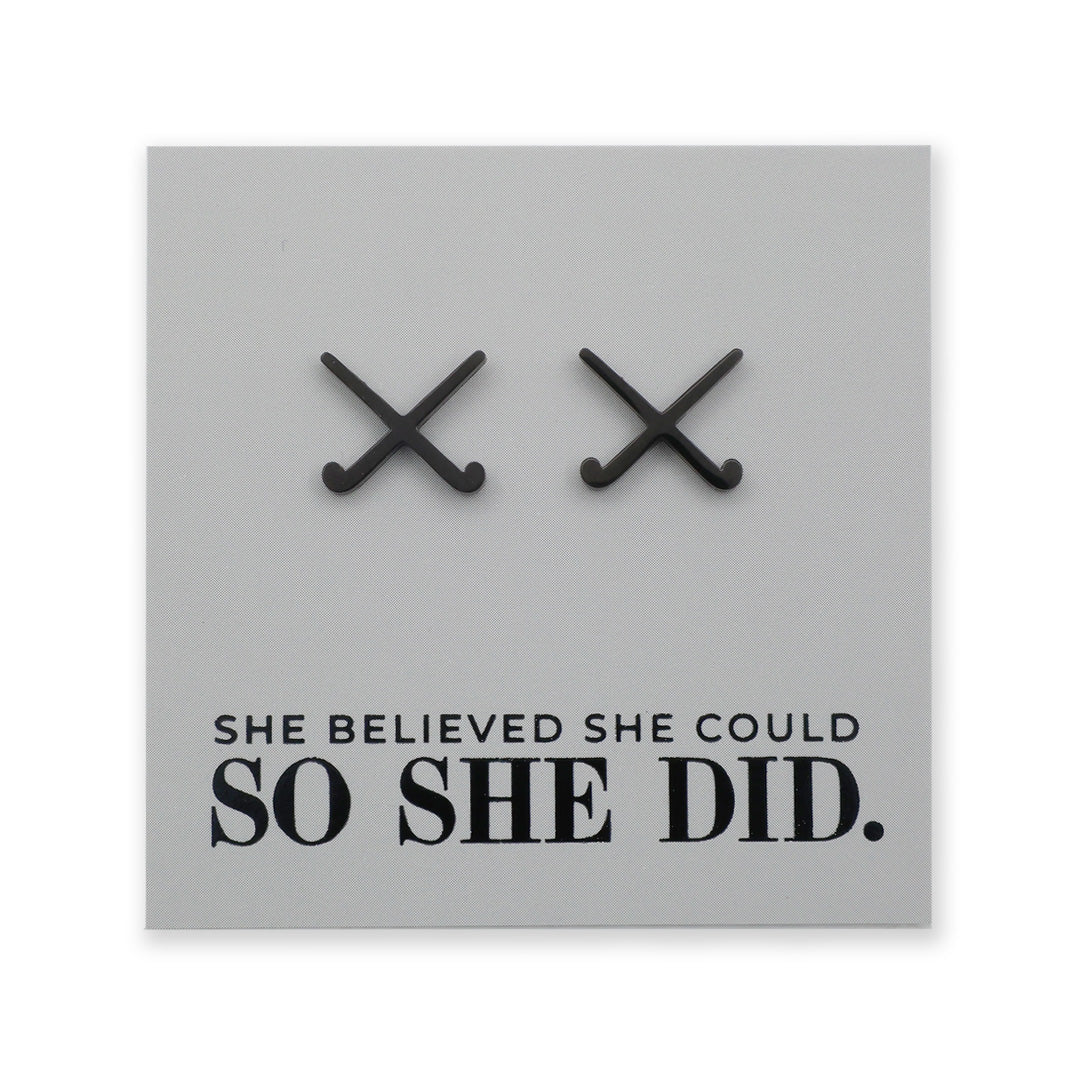 Black field hockey earrings on a grey card with 'She believed she could so she did' text