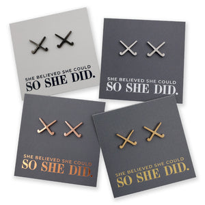 Four pairs of field hockey earrings on grey cards with 'She believed she could so she did' text.