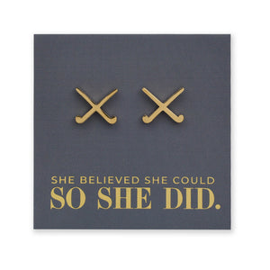 Gold stainless steel hockey shaped earrings on a dark grey card with 'She believed she could so she did' text