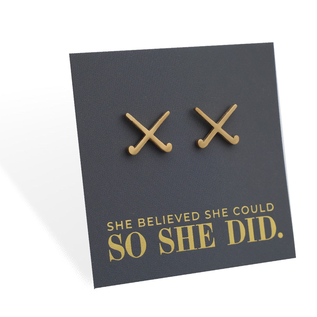 Gold stainless steel hockey earrings on a grey card with 'She believed she could so she did' text