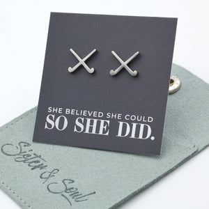Silver stainless steel hockey earrings on a card with 'She believed she could so she did' text, displayed on a branded card.