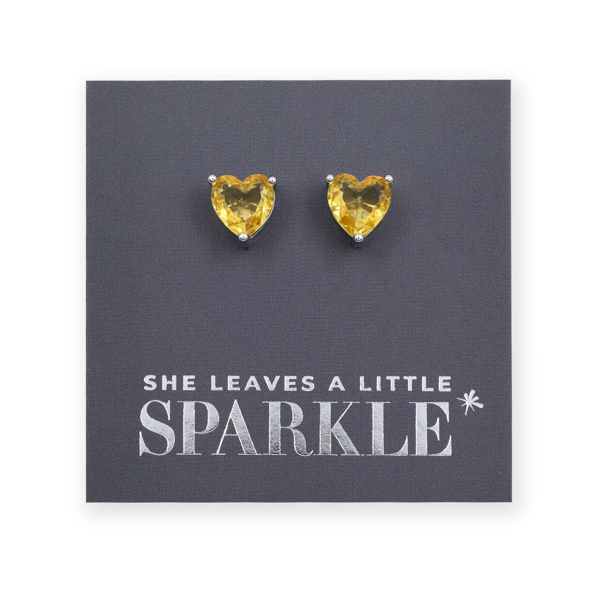 Heart-shaped yellow gemstone earrings on a card with 'She leaves a little sparkle' text.