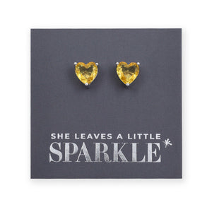 Heart-shaped yellow gemstone earrings on a card with 'She leaves a little sparkle' text.