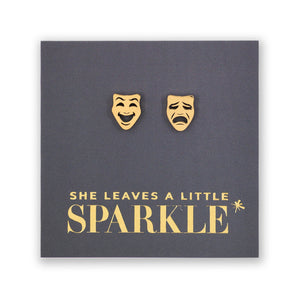 Gold theater mask earrings on a dark gray card with 'She Leaves a Little Sparkle' text.