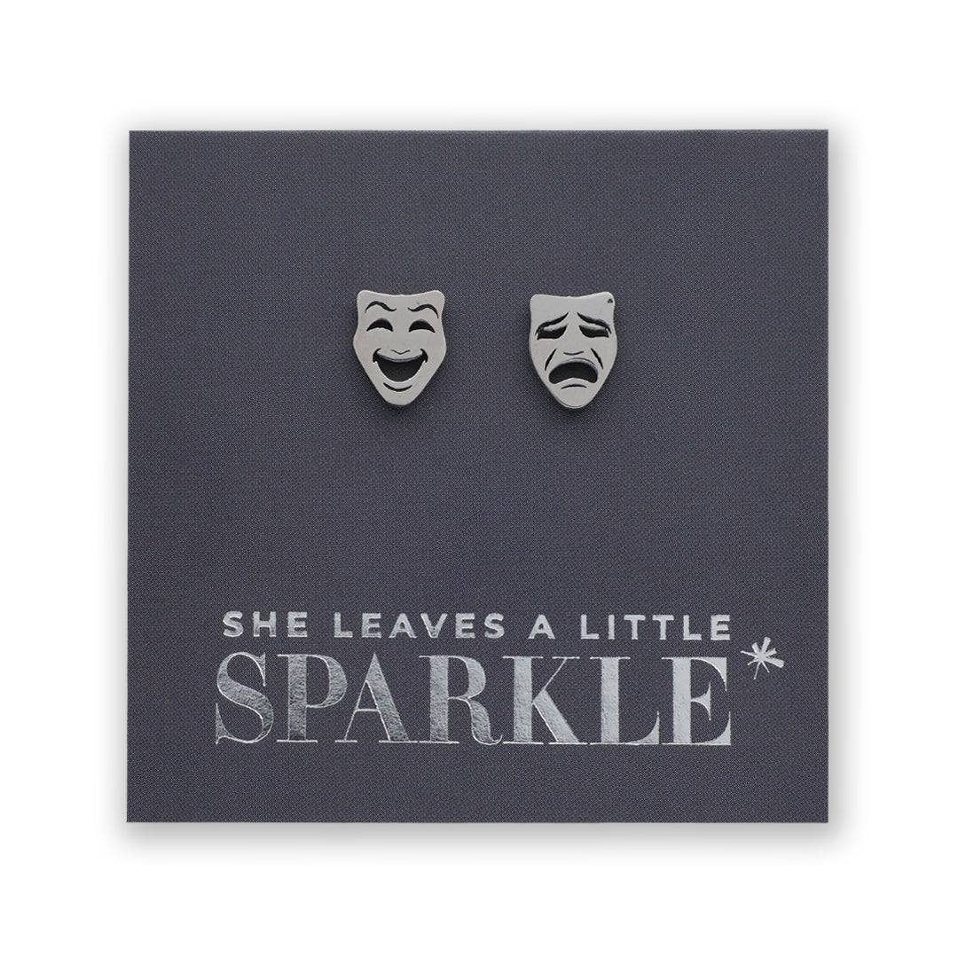 Earrings shaped like comedy and tragedy masks on a card with 'She Leaves a Little Sparkle' text.
