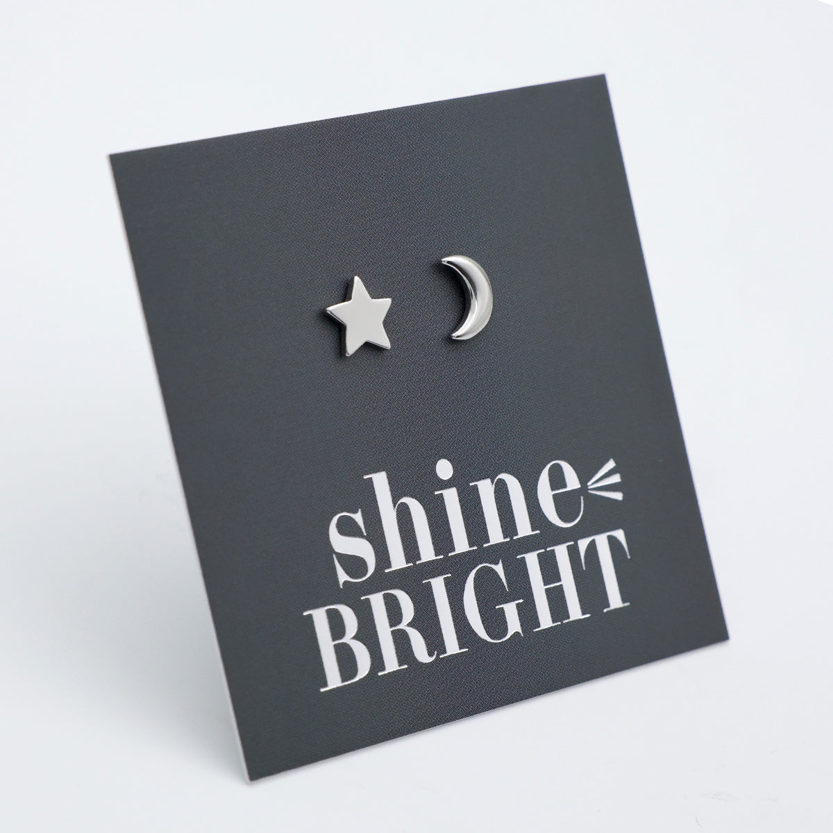 Silver star and moon earrings on a dark gray card with 'shine bright' text.