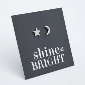 Silver star and moon earrings on a black card with 'shine bright' text.