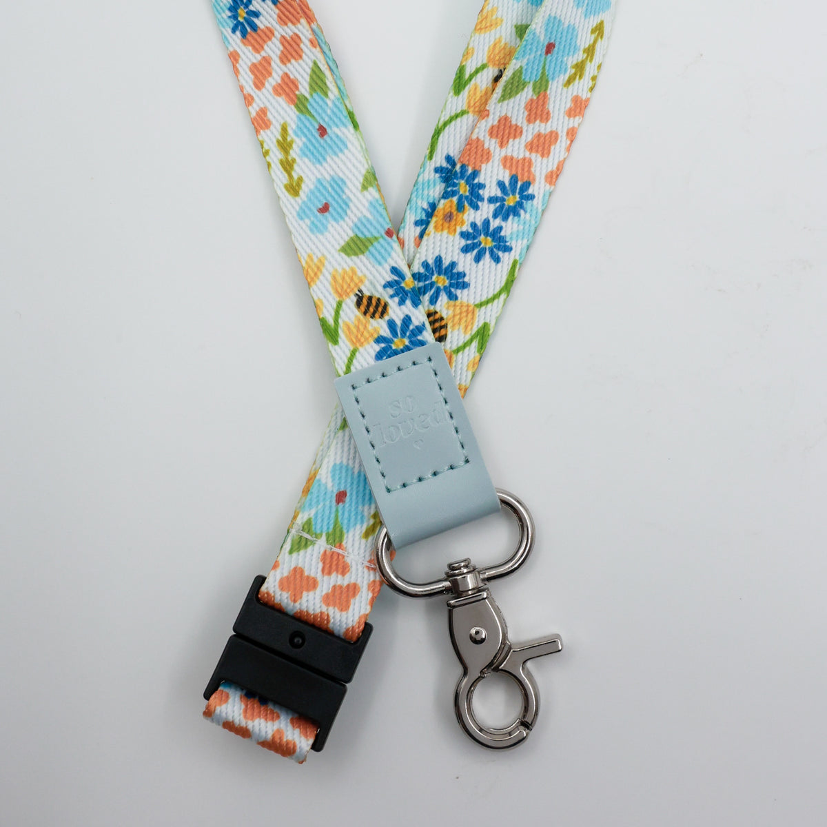 So Loved embossed on a colourful floral lanyard with pale blue trim and a lobster clasp.