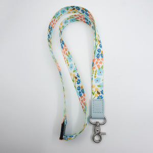 Teach Love Inspire embossed on a colourful floral lanyard with pale blue trim and a lobster clasp.