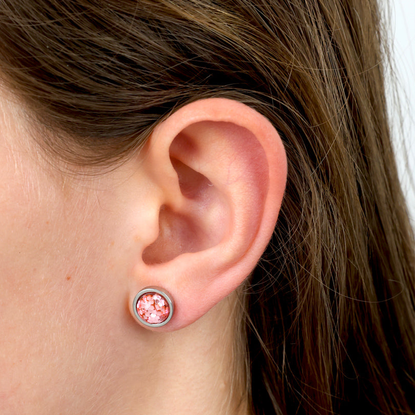 Close-up of an ear wearing a pink gemstone stud earring.