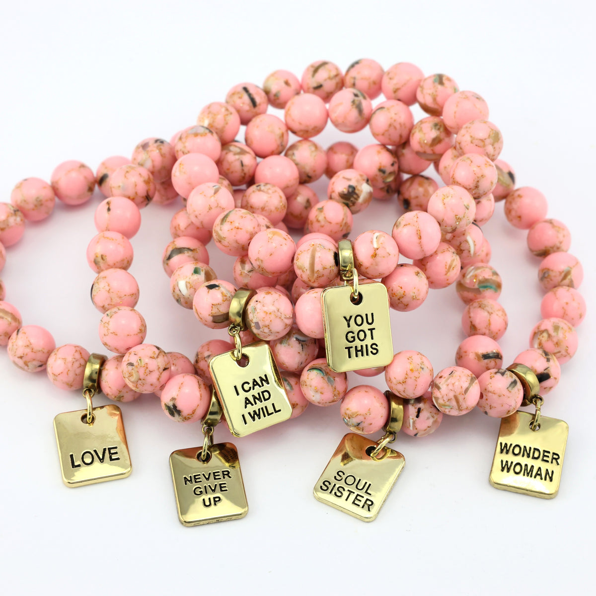Pink beaded bracelets with gold charms on a white background