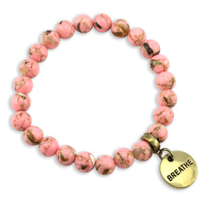 Pink beaded bracelet with a gold 'BREATHE' charm on a white background
