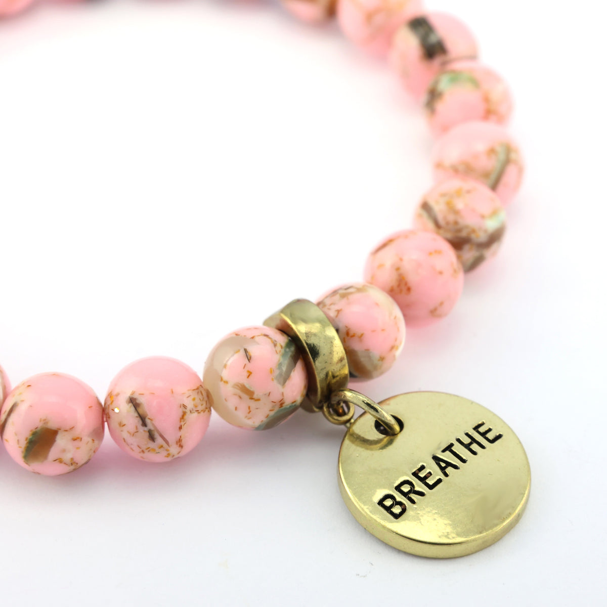 Pink beaded bracelet with a gold 'BREATHE' tag on a white background