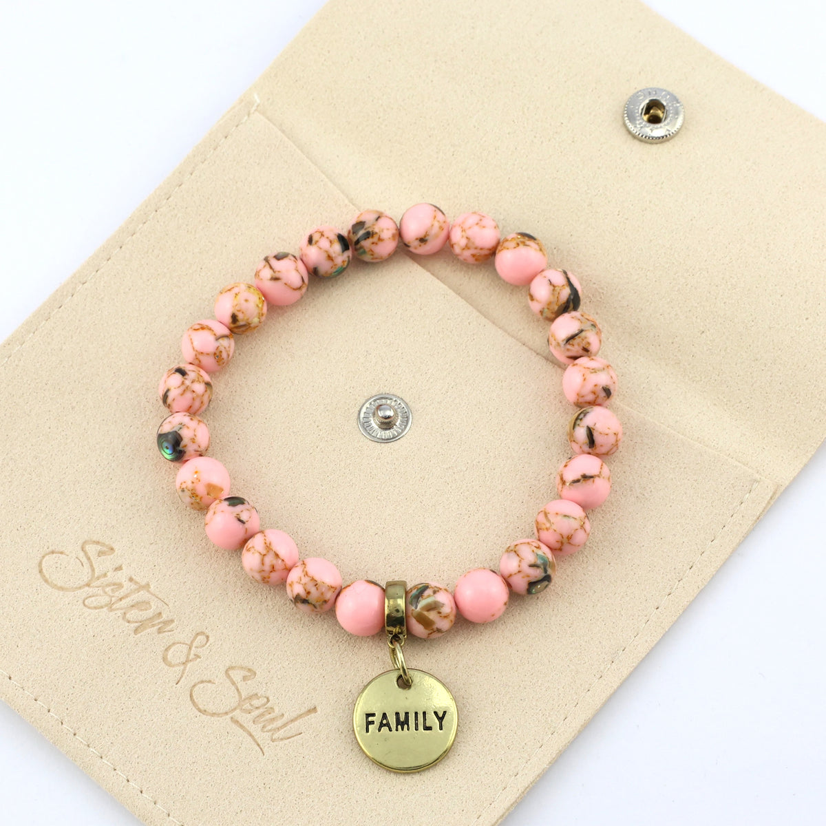 Pink beaded bracelet with 'FAMILY' charm on a beige card