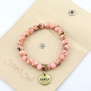 Pink beaded bracelet with 'FAMILY' charm on a beige card