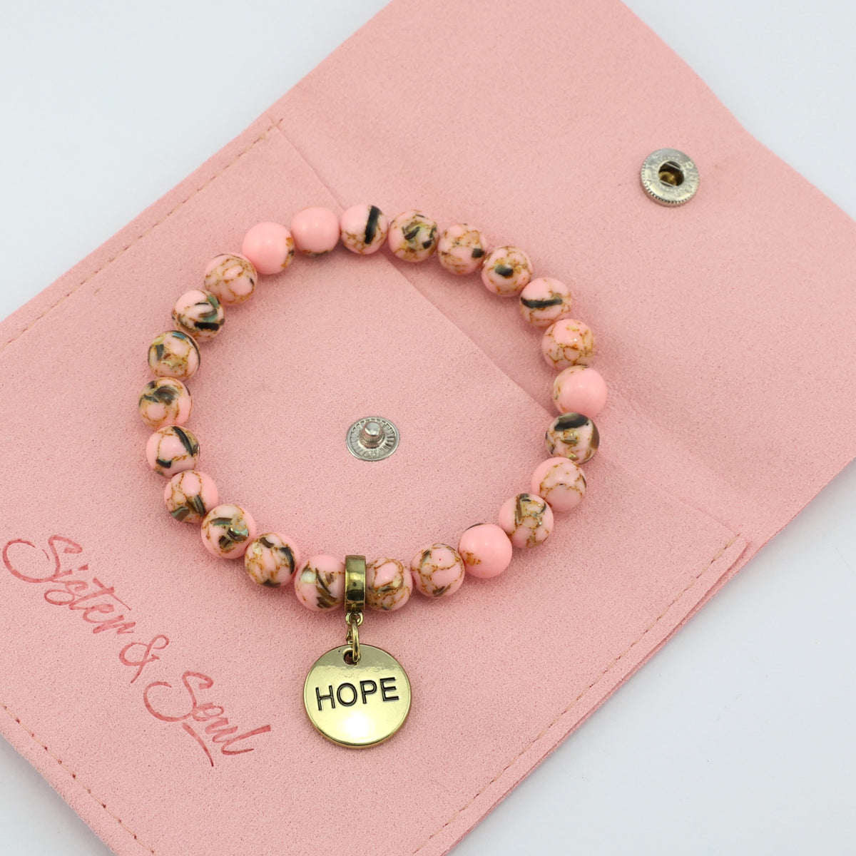 Beaded bracelet with 'HOPE' charm on a pink pouch