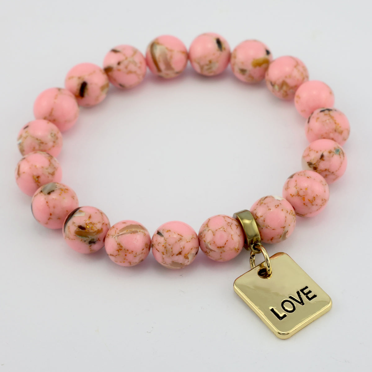 Pink beaded bracelet with a gold 'LOVE' charm on a light gray background