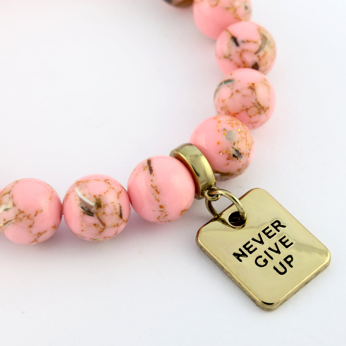 Pink beaded bracelet with a gold 'Never Give Up' charm on a white background