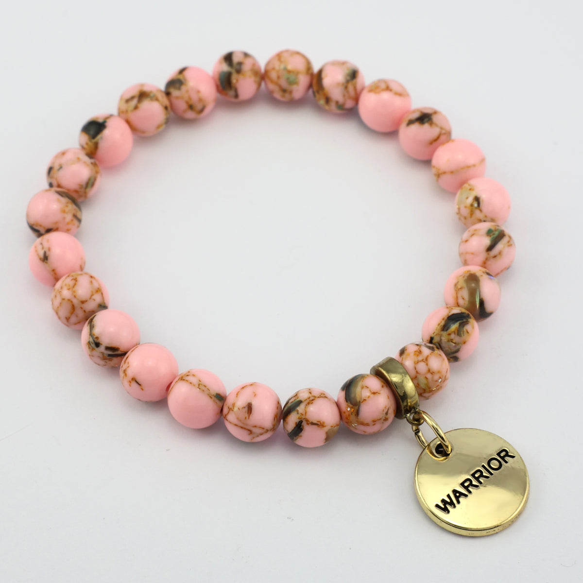 Pink beaded bracelet with a gold 'WARRIOR' charm on a light gray background