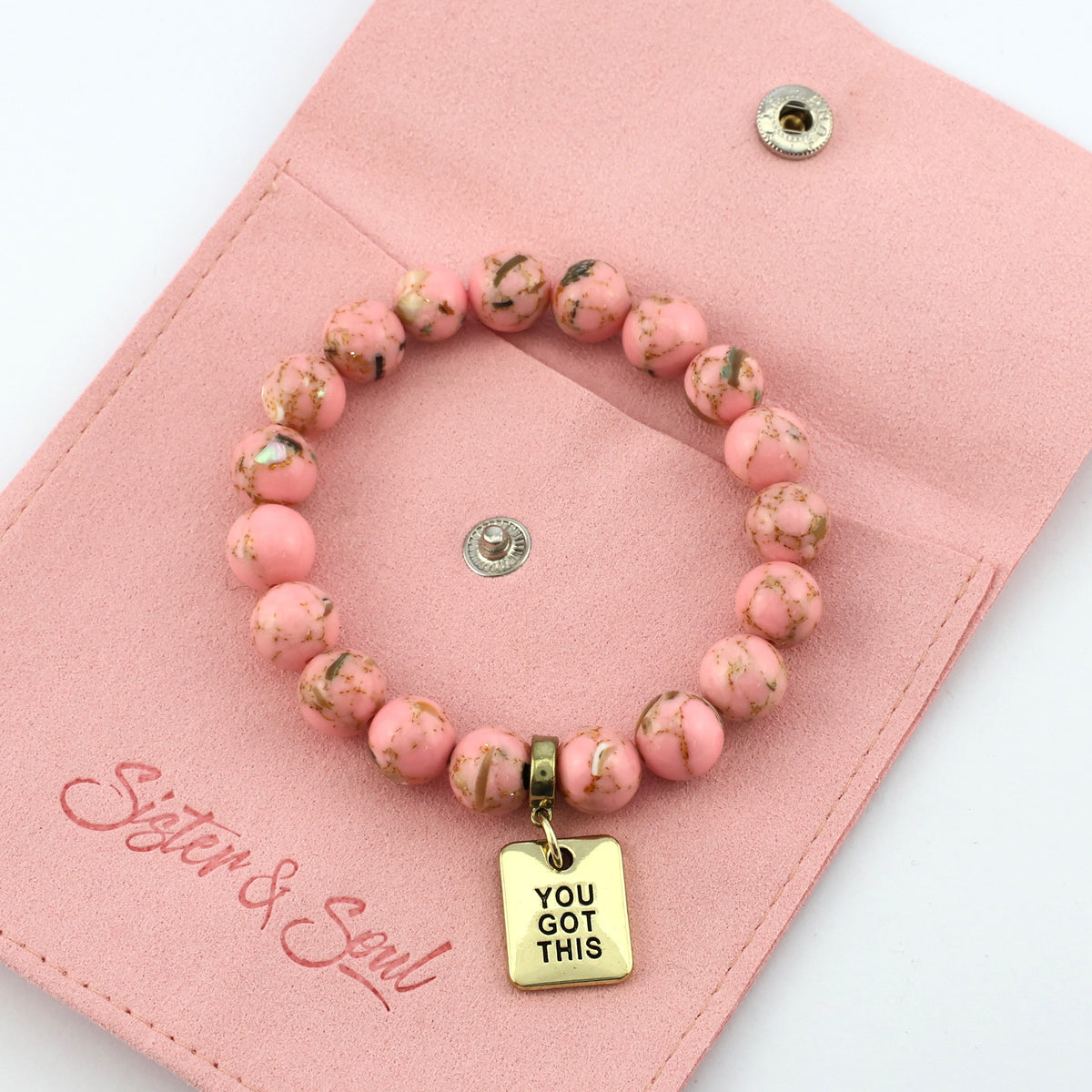 Pink beaded bracelet with gold 'You Got This' charm on a pink pouch with 'Sister & Soul' branding.