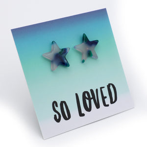 A pair of star-shaped stud earrings with a marbled blue, green, and white pattern, displayed on a square card that reads 'SO LOVED' against a clean white background.