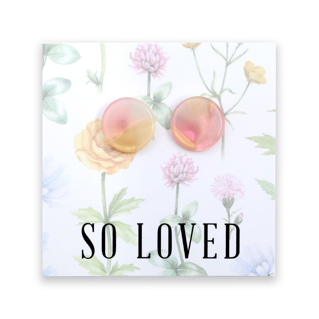 A pair of round, translucent earrings with a pink and yellow gradient, displayed on a white floral backing card with the text 'SO LOVED' at the bottom.