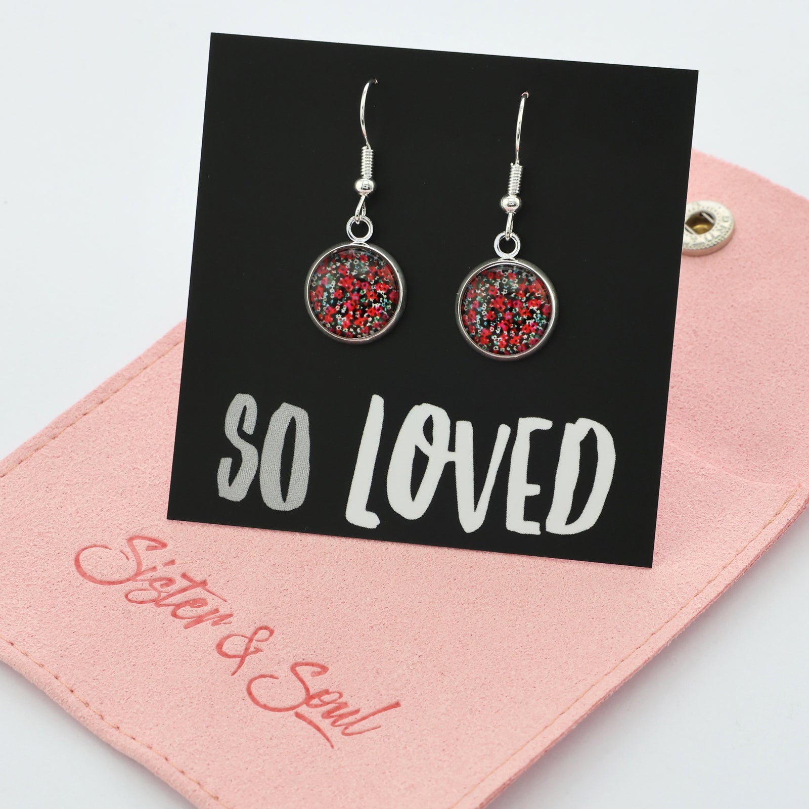 Pair of earrings with red and silver design on a 'SO LOVED' card