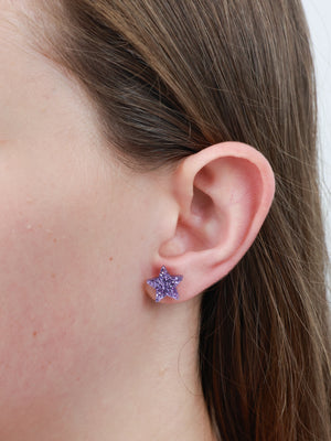 She Leaves A Little Sparkle star acrylic glitter stud earrings in light purple worn on an ear to show size and fit