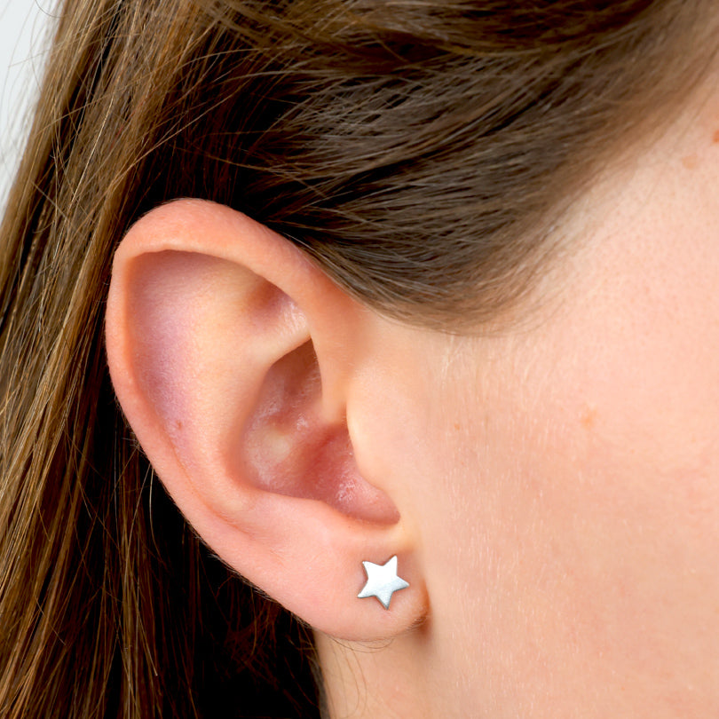 Close-up of an ear wearing a star-shaped silver earring.