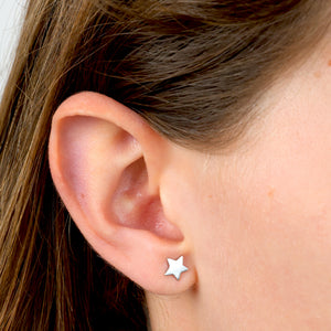 Close-up of an ear wearing a star-shaped silver earring.