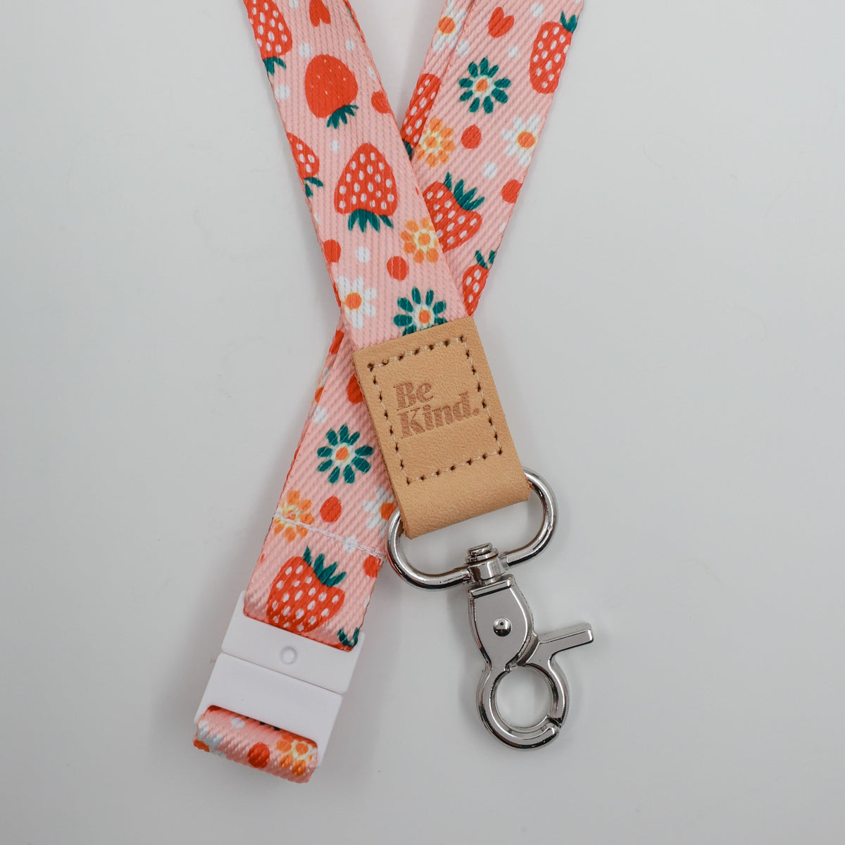 Be Kind embossed on a pink strawberry and flower lanyard with tan trim and a lobster clasp.