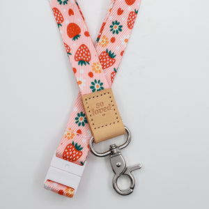 So Loved embossed on a pink strawberry and flower lanyard with tan trim and a lobster clasp.