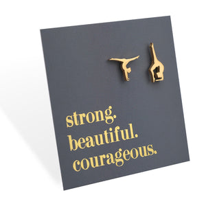 Gold stainless steel gymnast earrings on a dark grey card with 'strong. beautiful. courageous.' text