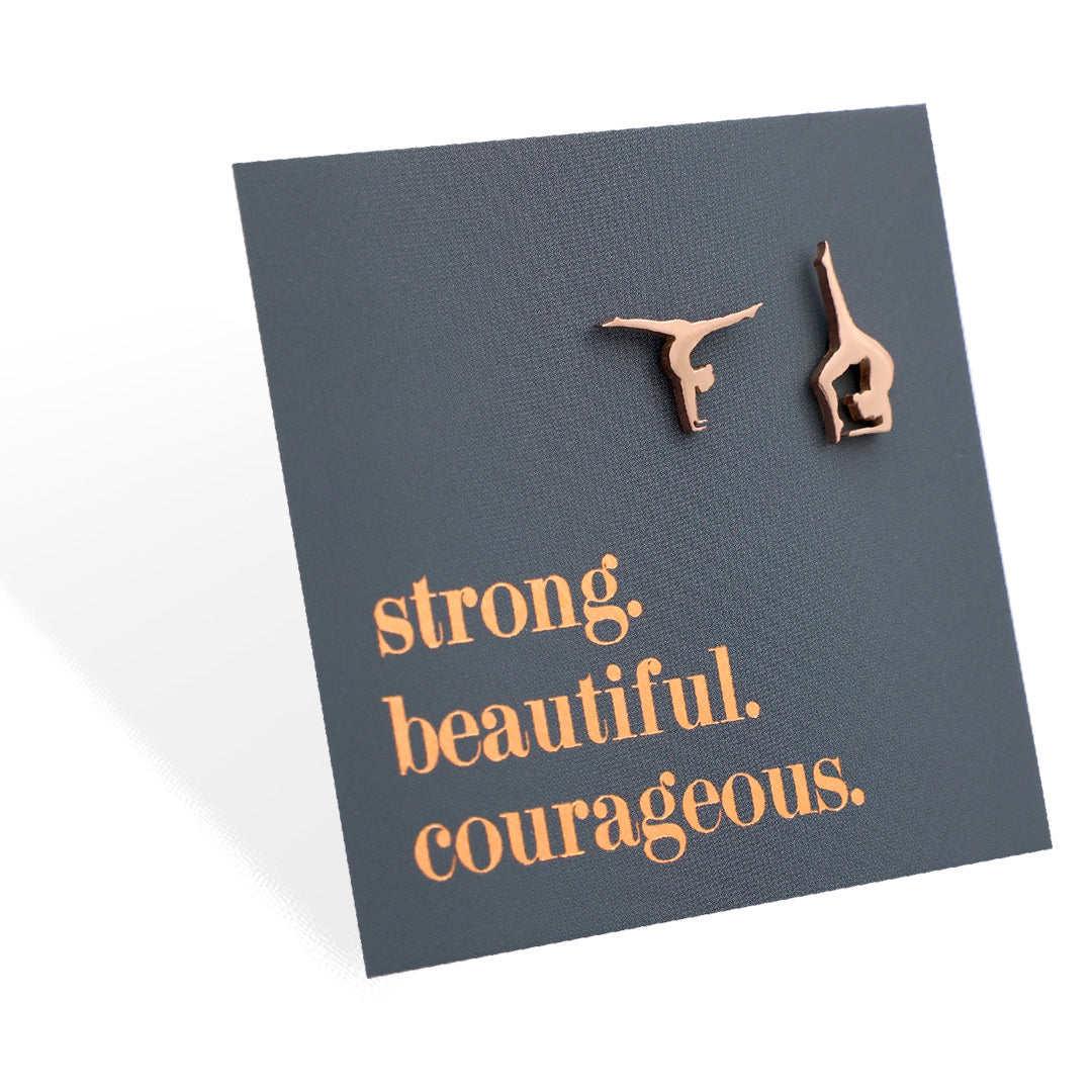 Rose gold gymnastics earrings on a card with 'strong. beautiful. courageous.' text