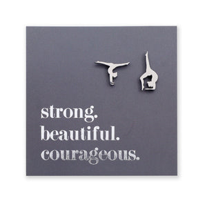 Silver hypoallergenic stainless steel gymnastics figure shaped earrings on a grey card with 'strong. beautiful. courageous.' text