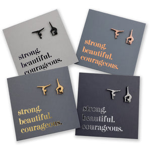 Four pairs of gymnastics earrings on gray cards with motivational phrases.