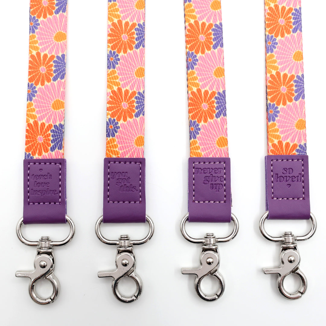 Four floral lanyards with purple ends and silver hooks on a white background.