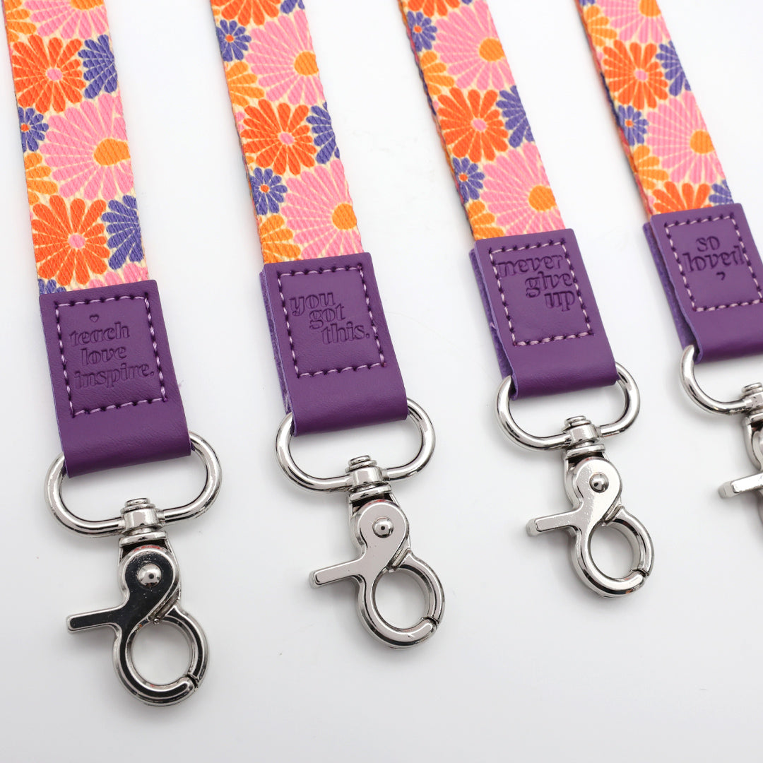 Floral patterned lanyards with purple accents and metal hooks on a white background