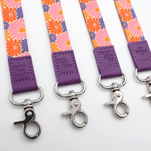 Floral patterned lanyards with purple accents and metal hooks on a white background