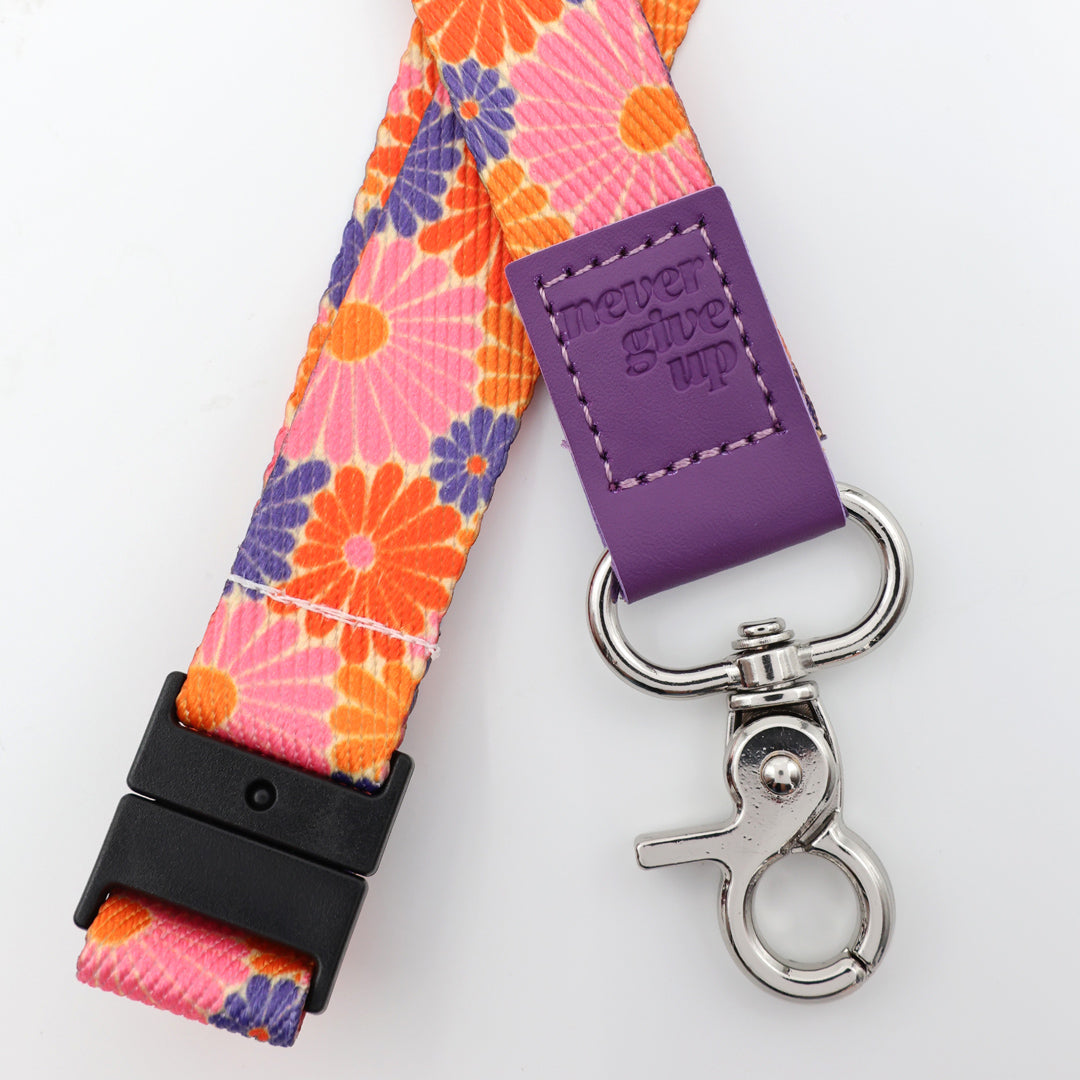 Colorful floral lanyard with purple tag and silver clip on a white background