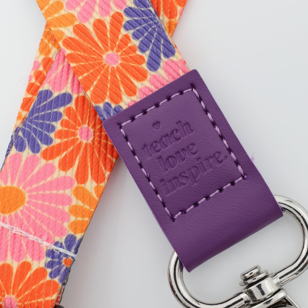 Four floral lanyards with purple ends and silver hooks on a white background.