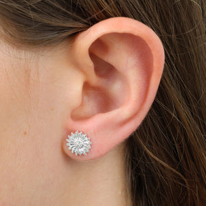 Close-up of an ear wearing a silver floral stud earring.