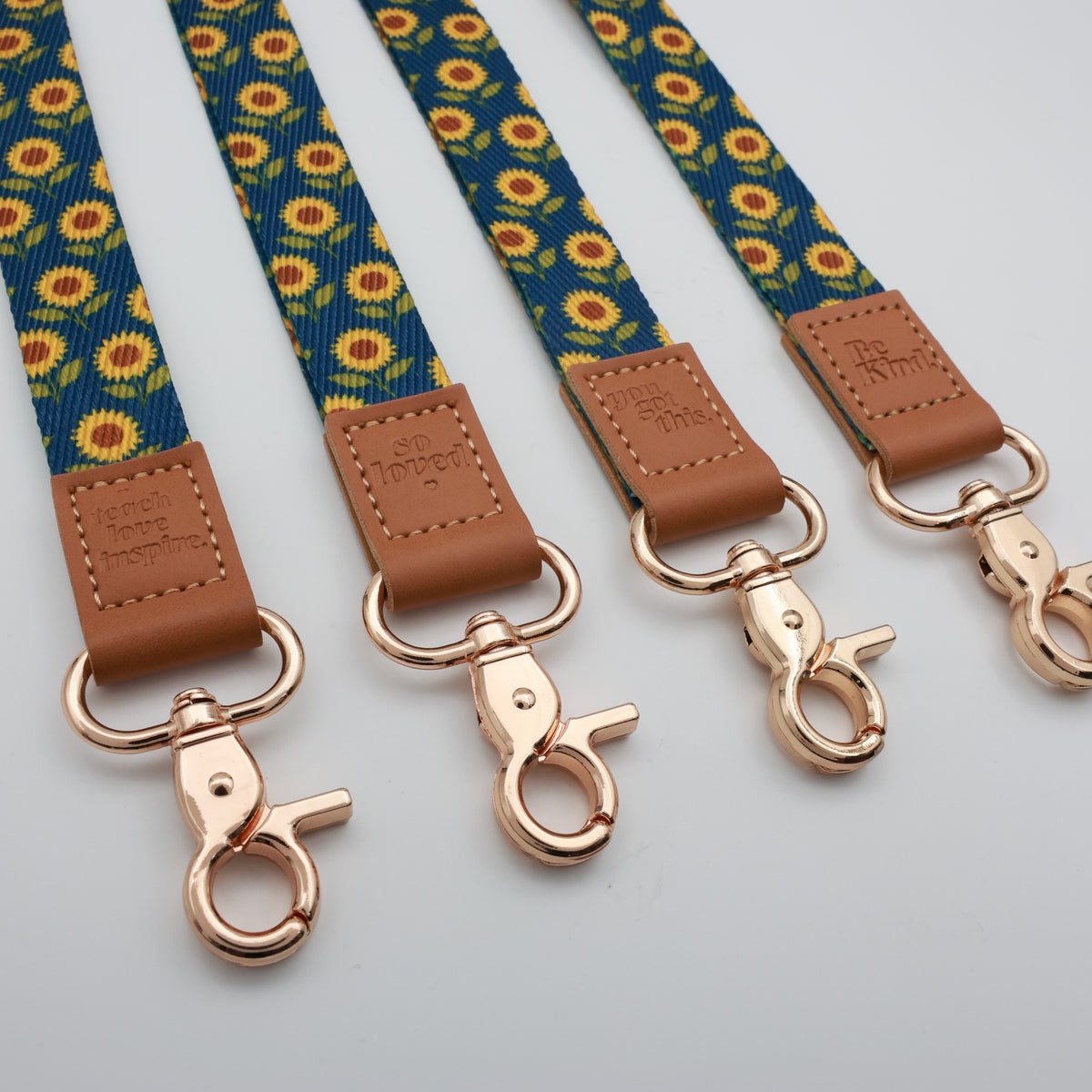 Sunflowers lanyards showing Be Kind, Teach Love Inspire, You Got This and So Loved embossed trims and lobster clasps.