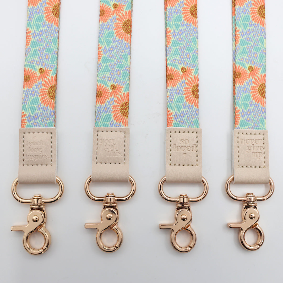 Four floral patterned straps with rose gold hooks on a light gray background