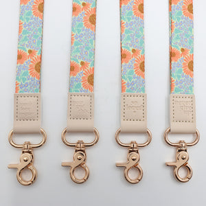 Four floral patterned straps with rose gold hooks on a light gray background