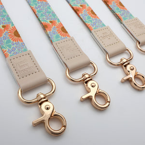 Floral patterned straps with gold hooks on a light gray background